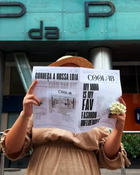 Pessoa lendo o jornal do Coolab das Mães na entrada do shopping